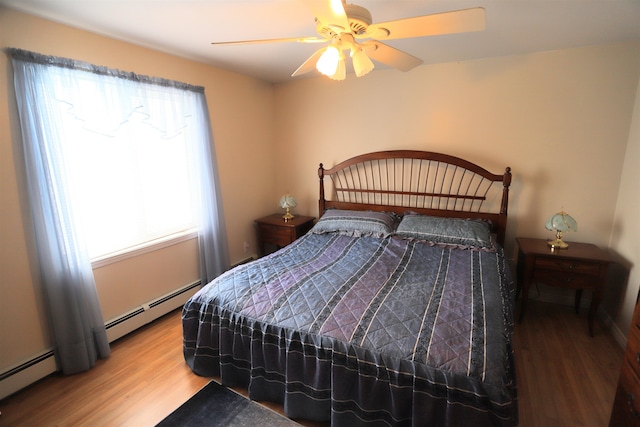 bedroom with ceiling fan, light hardwood / wood-style floors, and a baseboard heating unit