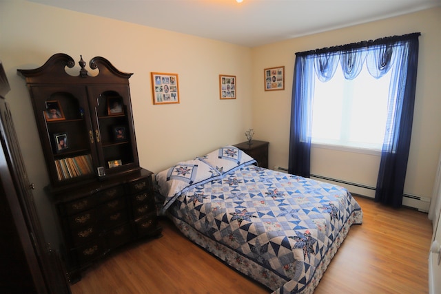 bedroom with wood-type flooring and baseboard heating