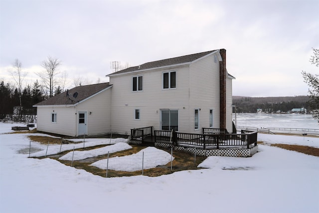 snow covered rear of property with a wooden deck