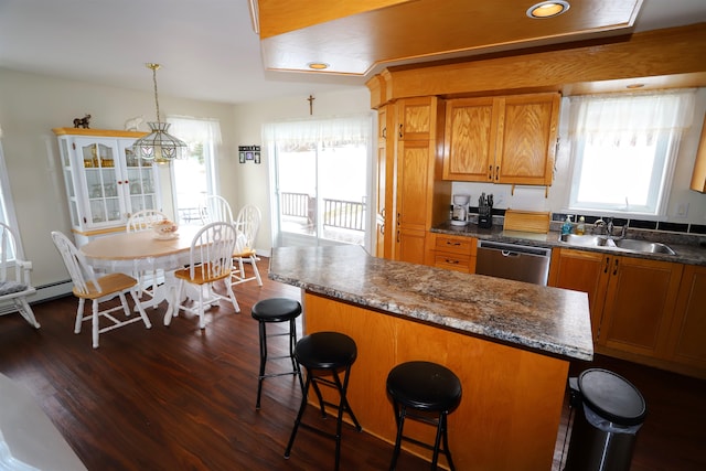 kitchen with sink, dark wood-type flooring, a breakfast bar, decorative light fixtures, and stainless steel dishwasher