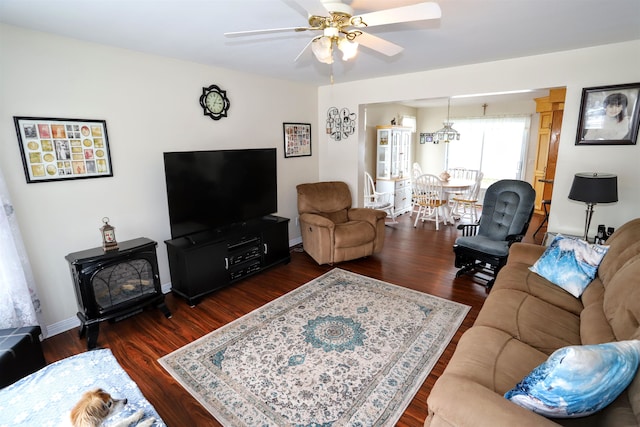 living room featuring a wood stove, dark wood-type flooring, and ceiling fan