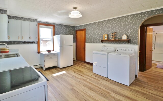 clothes washing area with baseboard heating, light hardwood / wood-style floors, sink, washer and clothes dryer, and ornamental molding