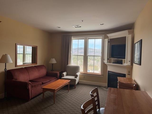 carpeted living area featuring baseboards, visible vents, and a fireplace