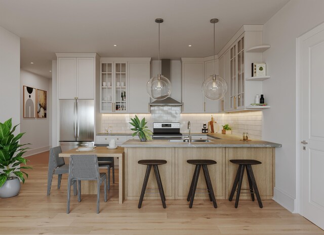 kitchen with decorative backsplash, wall chimney range hood, appliances with stainless steel finishes, and a sink