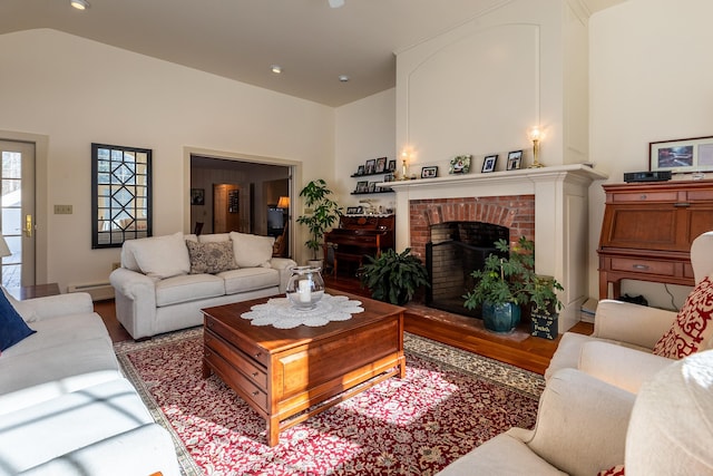 living room featuring lofted ceiling, wood-type flooring, a fireplace, and a baseboard heating unit