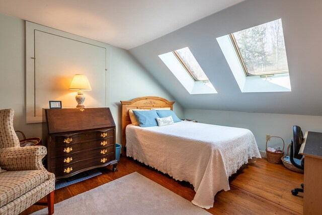 bedroom featuring dark wood-type flooring and vaulted ceiling with skylight