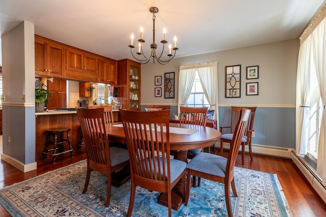 dining area featuring dark wood-type flooring, a baseboard radiator, and an inviting chandelier