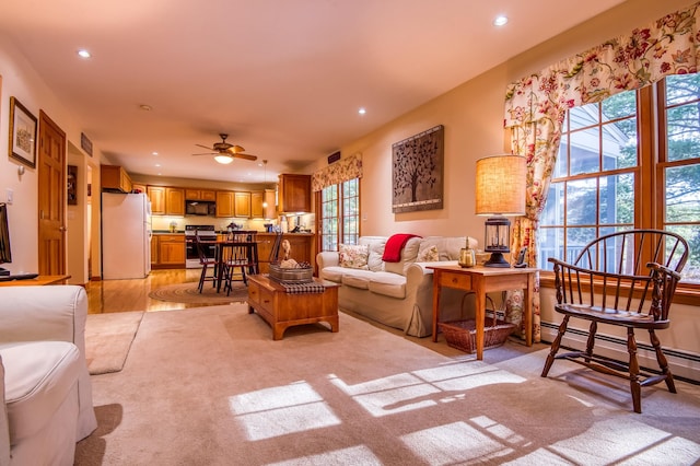 living room featuring a baseboard heating unit, light hardwood / wood-style flooring, and ceiling fan