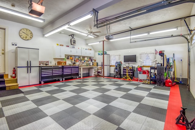 garage with white refrigerator, a garage door opener, and a workshop area