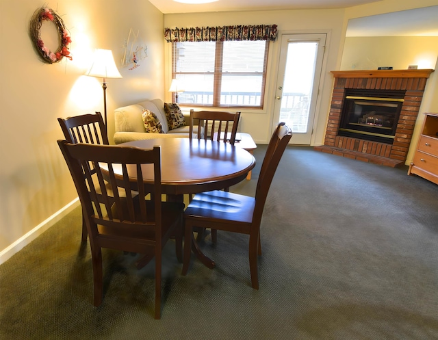 dining room featuring a brick fireplace and dark carpet