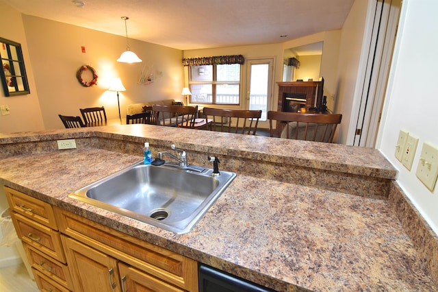 kitchen with decorative light fixtures, sink, and a brick fireplace