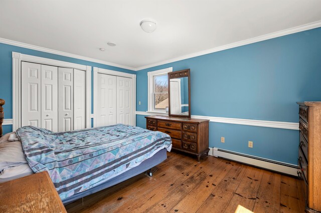 bedroom with two closets, a baseboard radiator, crown molding, and dark wood-type flooring