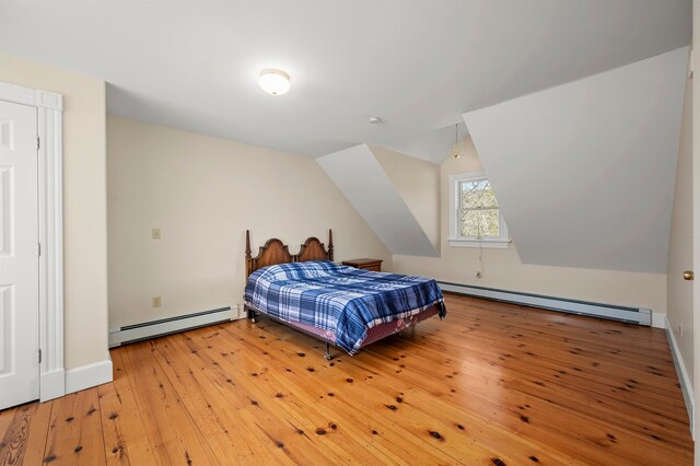bedroom featuring vaulted ceiling, light hardwood / wood-style floors, and a baseboard heating unit