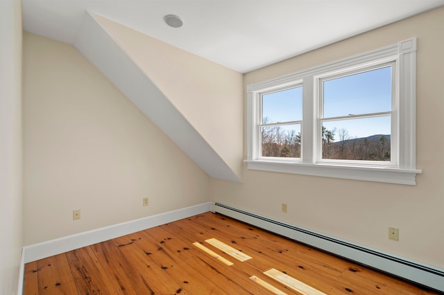 spare room with light hardwood / wood-style flooring, lofted ceiling, and a baseboard heating unit