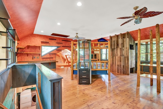 interior space with plenty of natural light, ceiling fan, vaulted ceiling with skylight, and light wood-type flooring