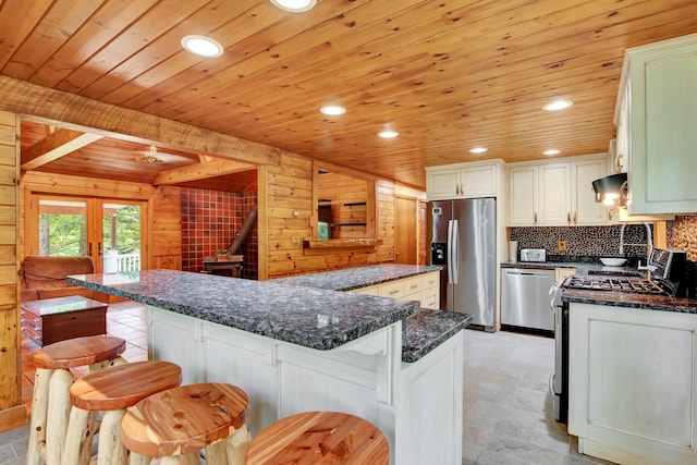 kitchen with stainless steel appliances, wooden walls, wooden ceiling, a kitchen breakfast bar, and light tile floors