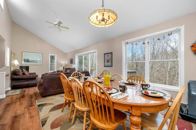 dining room featuring hardwood / wood-style flooring, ceiling fan with notable chandelier, and vaulted ceiling