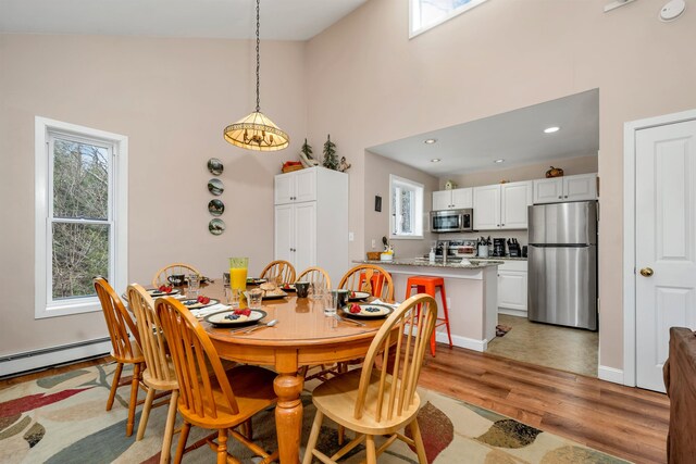 dining space featuring high vaulted ceiling and light hardwood / wood-style floors