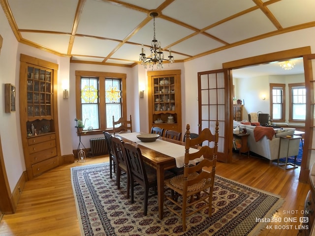 dining space featuring coffered ceiling, radiator, light wood-type flooring, and a notable chandelier