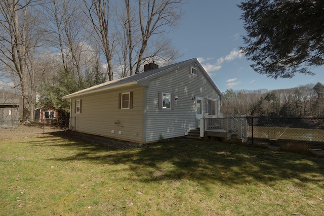 view of property exterior featuring a lawn, a chimney, and fence