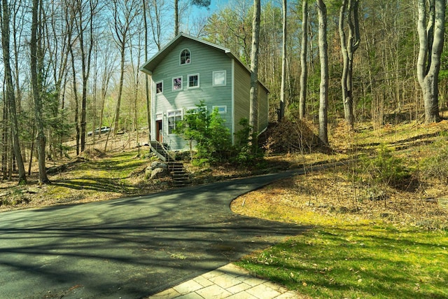 view of property exterior featuring a wooded view and driveway