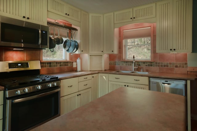 kitchen featuring cream cabinets, tasteful backsplash, appliances with stainless steel finishes, and a sink