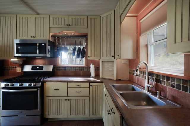 kitchen with decorative backsplash, sink, stainless steel appliances, and cream cabinetry