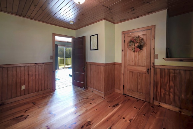 entryway with crown molding, wood ceiling, light hardwood / wood-style floors, and wood walls