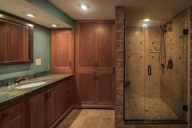 bathroom with a shower with shower door, vanity, and tile patterned flooring