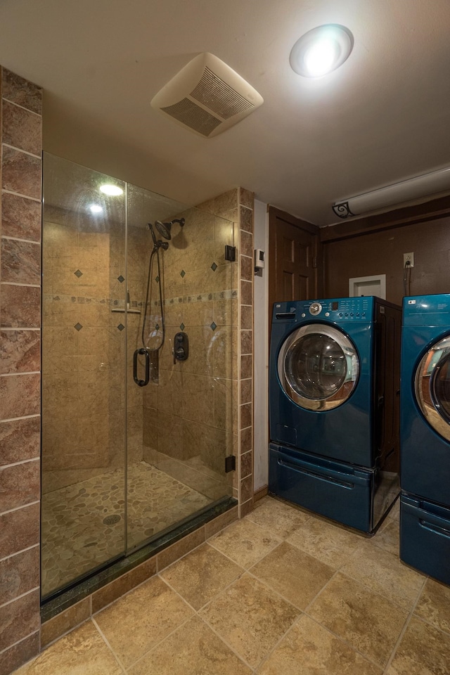 bathroom featuring washing machine and dryer and a shower with shower door