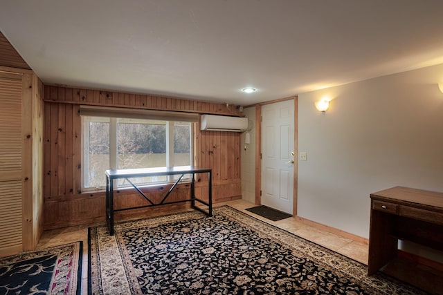 interior space with light tile patterned floors, wood walls, baseboards, and a wall unit AC