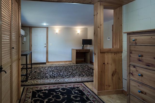 hall with tile patterned floors, concrete block wall, and baseboards