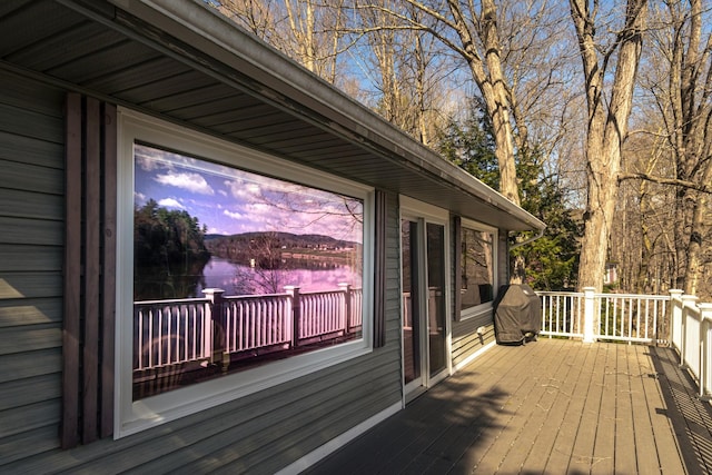 deck at dusk with a water view and a grill