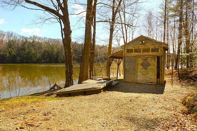 view of outdoor structure with an outbuilding, a forest view, and a water view