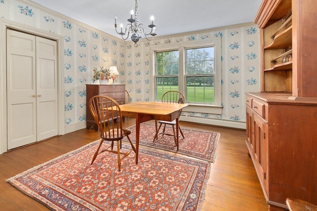 dining room with light hardwood / wood-style flooring, a notable chandelier, baseboard heating, and ornamental molding