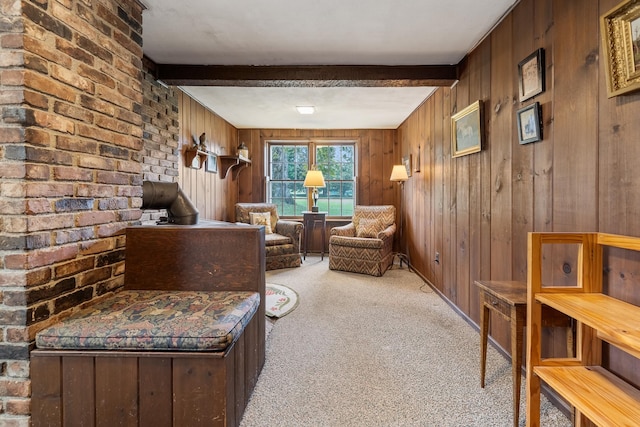 living room with light colored carpet, beam ceiling, wooden walls, and brick wall