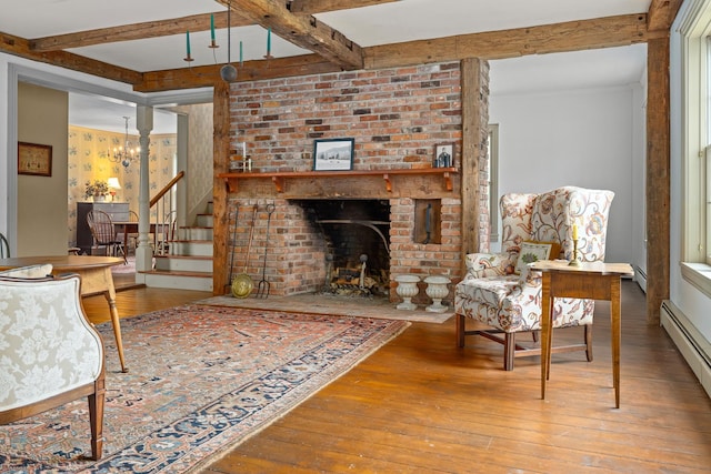 living room featuring beamed ceiling, hardwood / wood-style flooring, baseboard heating, and a brick fireplace