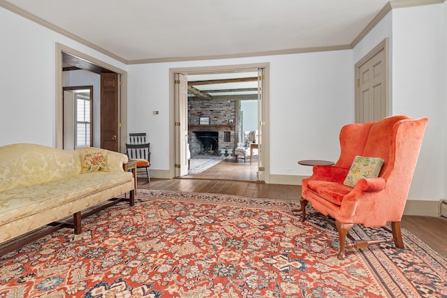 living area with hardwood / wood-style floors, brick wall, crown molding, and a fireplace