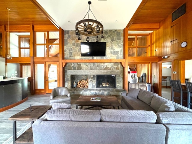 living room with a high ceiling, a fireplace, and wood walls