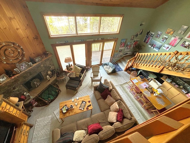 interior space featuring a stone fireplace, high vaulted ceiling, and wood walls