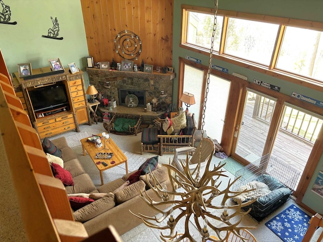 living room with wood walls, a towering ceiling, carpet floors, and a fireplace