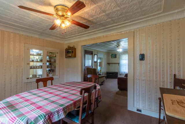 dining room featuring dark colored carpet, ornamental molding, and ceiling fan