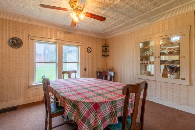 carpeted dining area with crown molding and ceiling fan