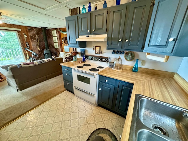 kitchen featuring light colored carpet, a wood stove, white electric stove, brick wall, and sink