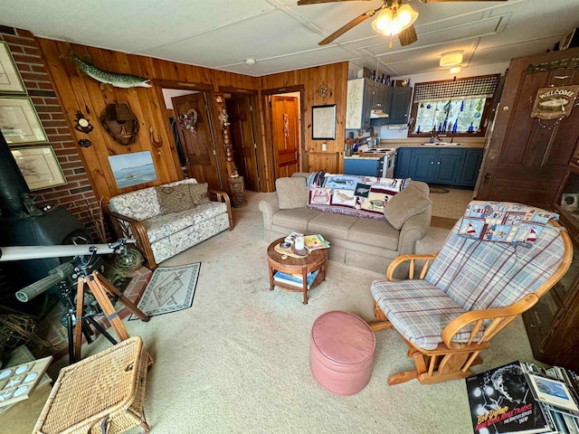 living room featuring ceiling fan, sink, brick wall, carpet flooring, and wood walls