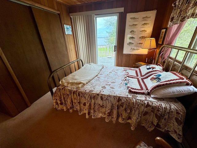 bedroom featuring wood walls and access to outside