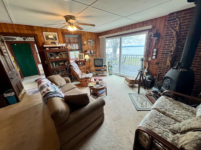 living room with wood walls, a wood stove, and carpet floors