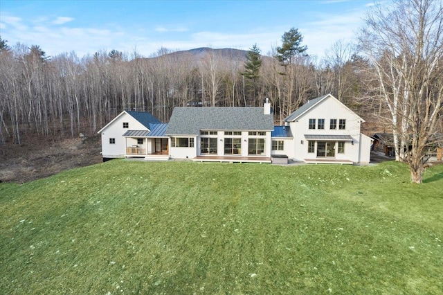 back of house with a yard, a deck, metal roof, and a standing seam roof