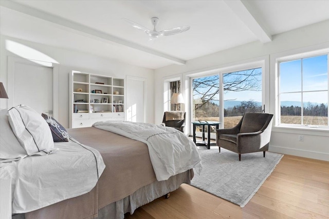 bedroom with wood finished floors, beam ceiling, a ceiling fan, baseboards, and access to exterior