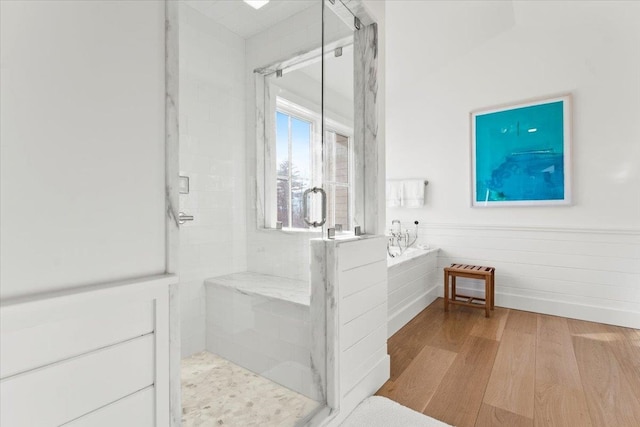 full bath with a stall shower, a garden tub, and wood finished floors